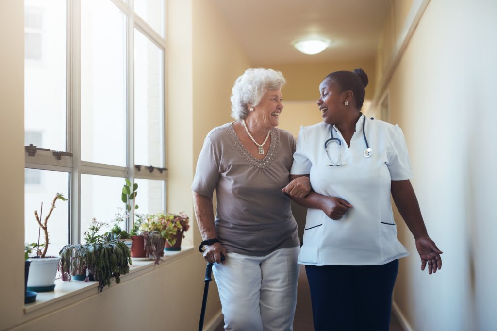 Smiling healthcare worker and senior woman walking together